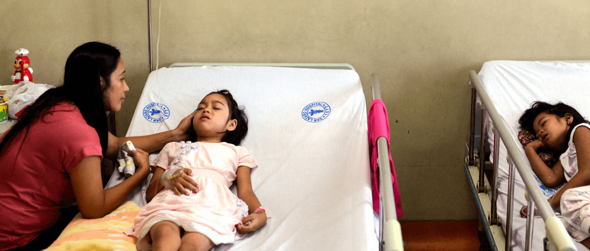 Fotografía de niños en camas de hospital siendo atendidos por