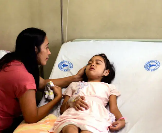 Niña en cama de hospital recibiendo cuidados