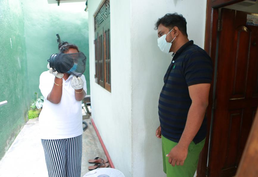 Un miembro del personal de WMP explica a Kasun Chameera cómo funciona una trampa para mosquitos.