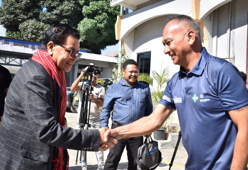 El ministro de Sanidad de Timor Oriental se reúne con un voluntario de « World Mosquito Program ». Se ve una cámara al fondo. 
